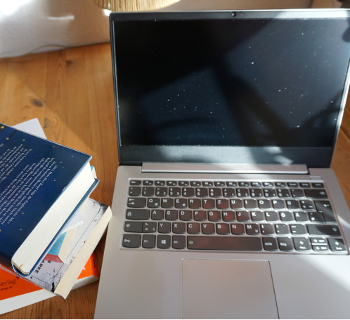 Aufgeklappter Laptop mit Büchern daneben