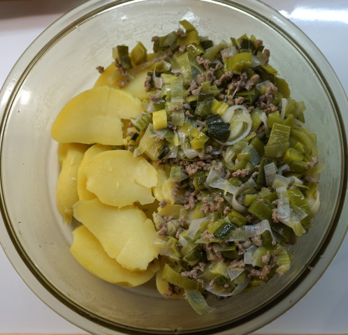 In einer Auflauform linke Hälfte mit Kartoffeln auf dem Boden, recht Hälfte mit gedünstetem Lauch über den Kartoffeln